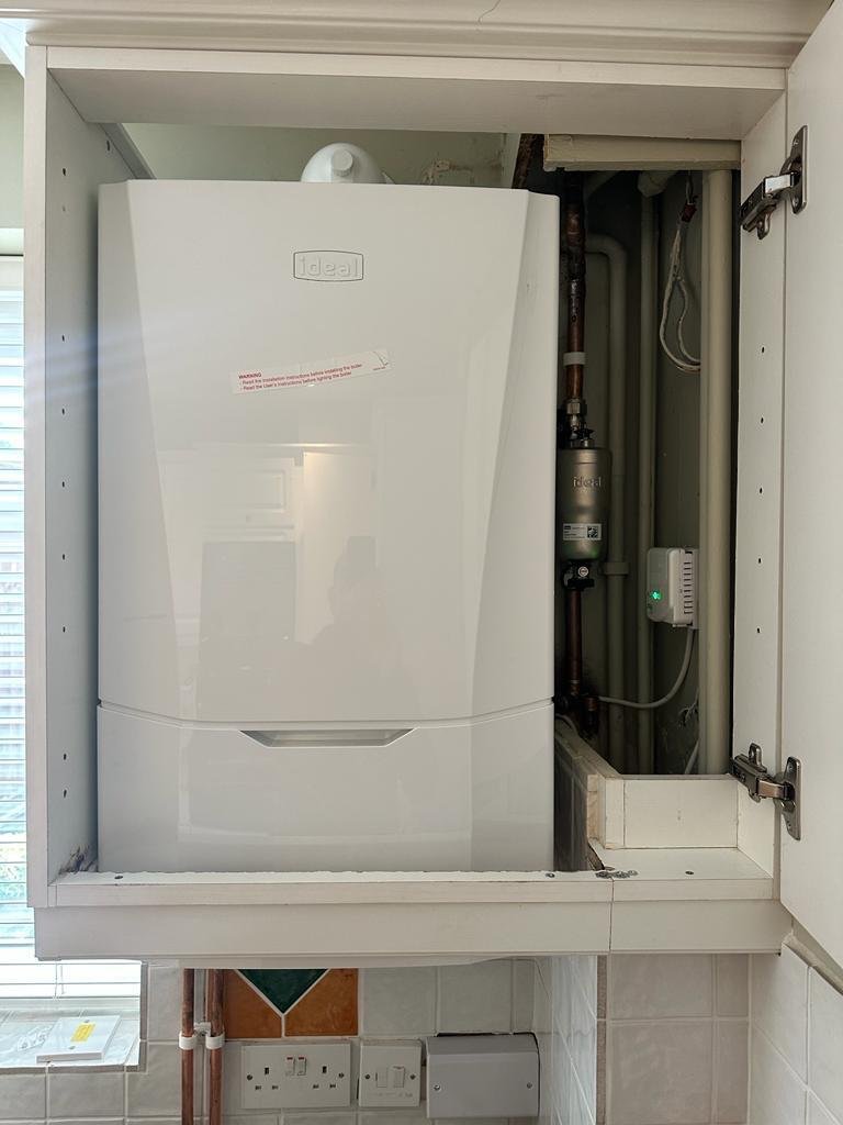 Ideal combi boiler and system filter installed neatly inside a white kitchen wall unit