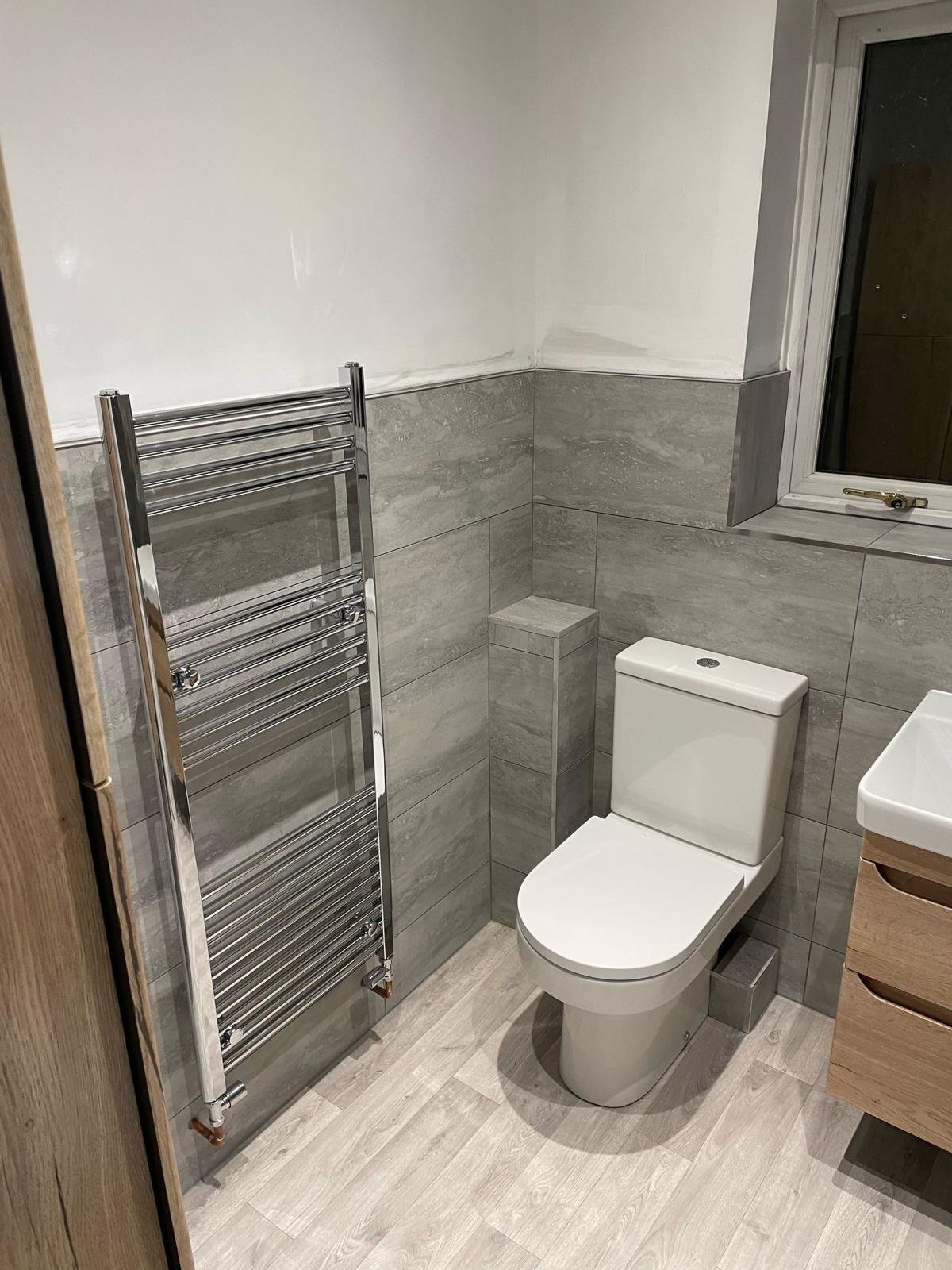 Bathroom with a close coupled toilet and a chrome heated towel rail