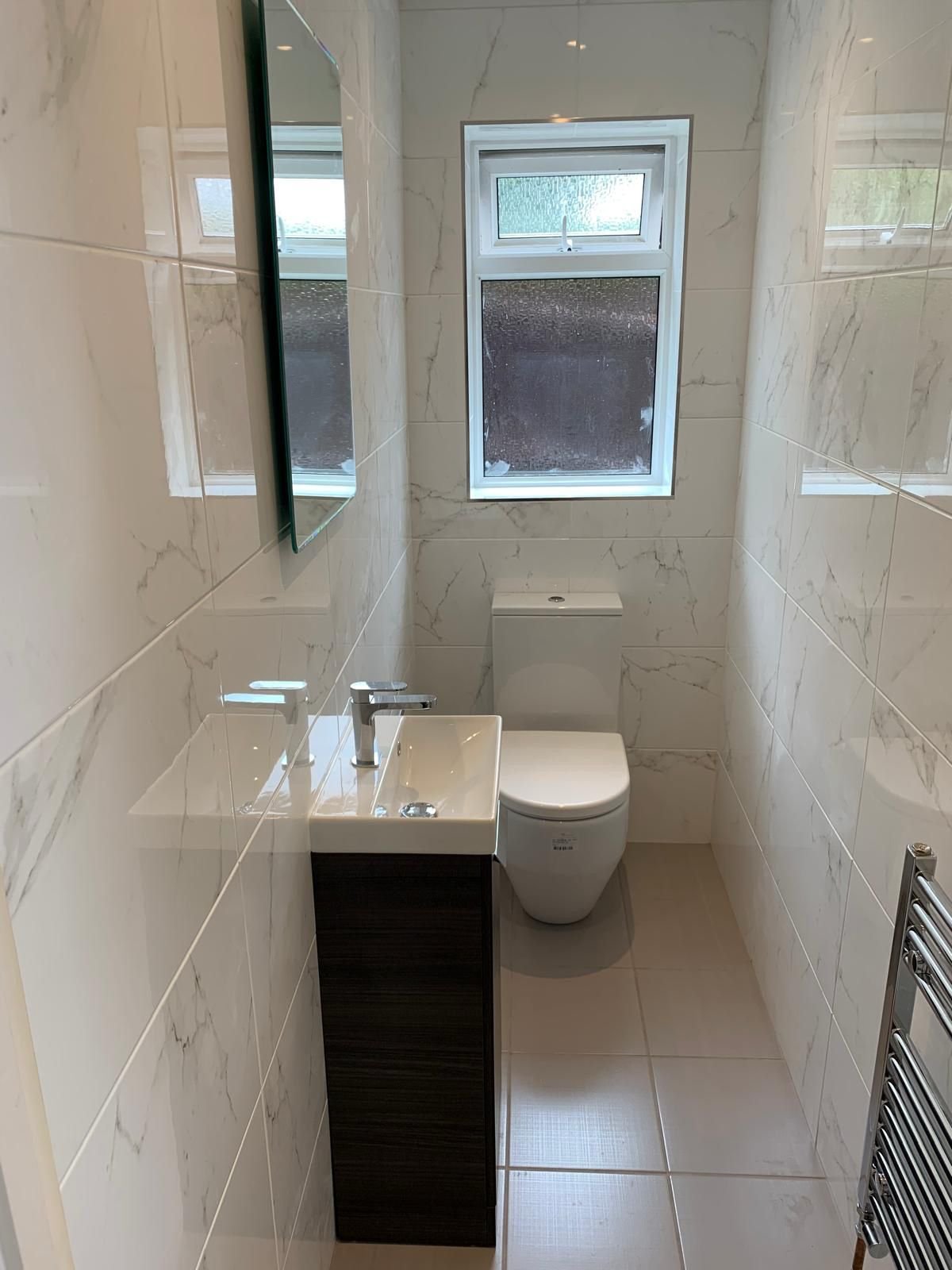 Completed downstairs cloakroom with marble effect tiling and a vanity unit