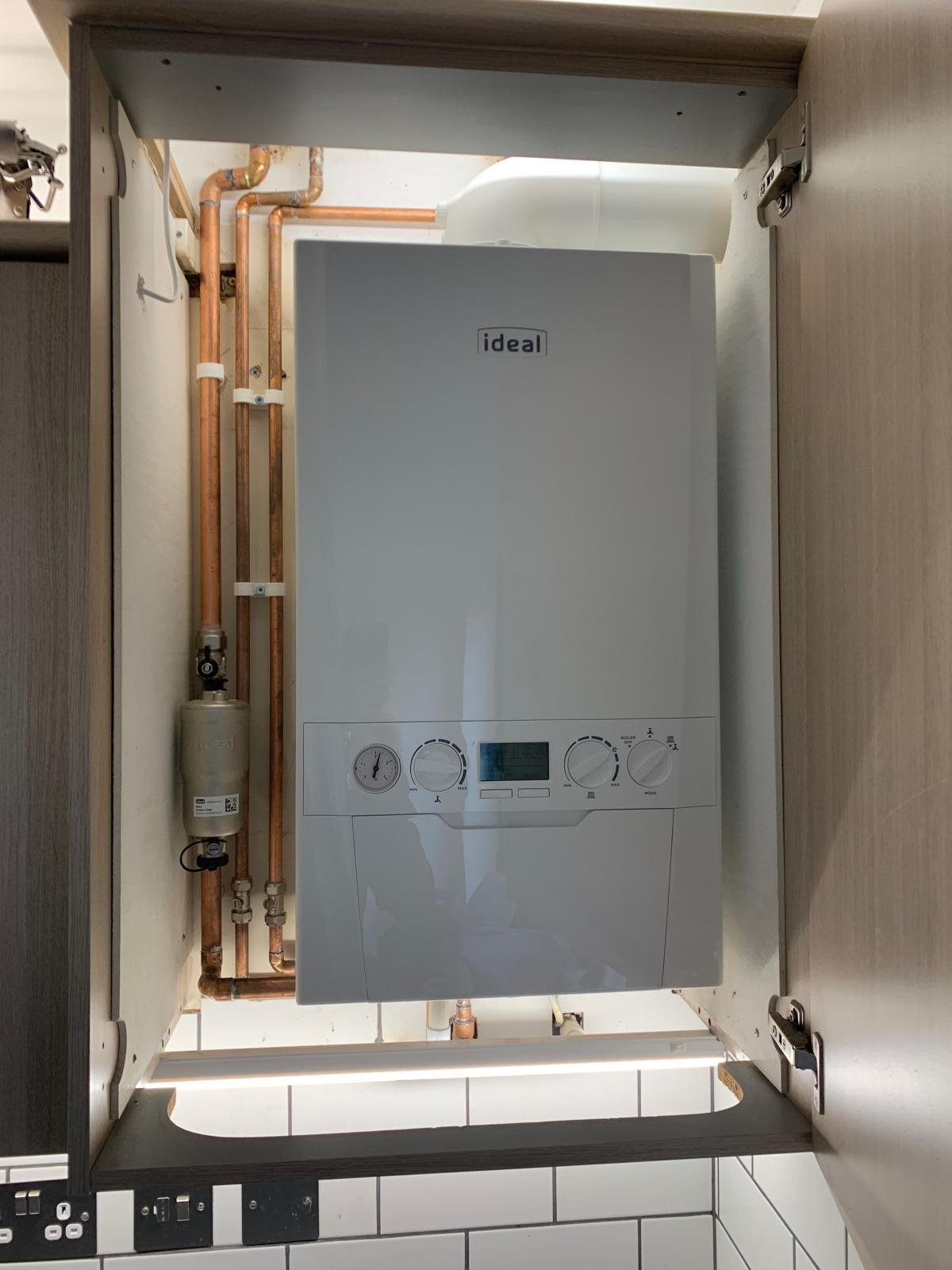 New combi boiler installation in a kitchen cupboard