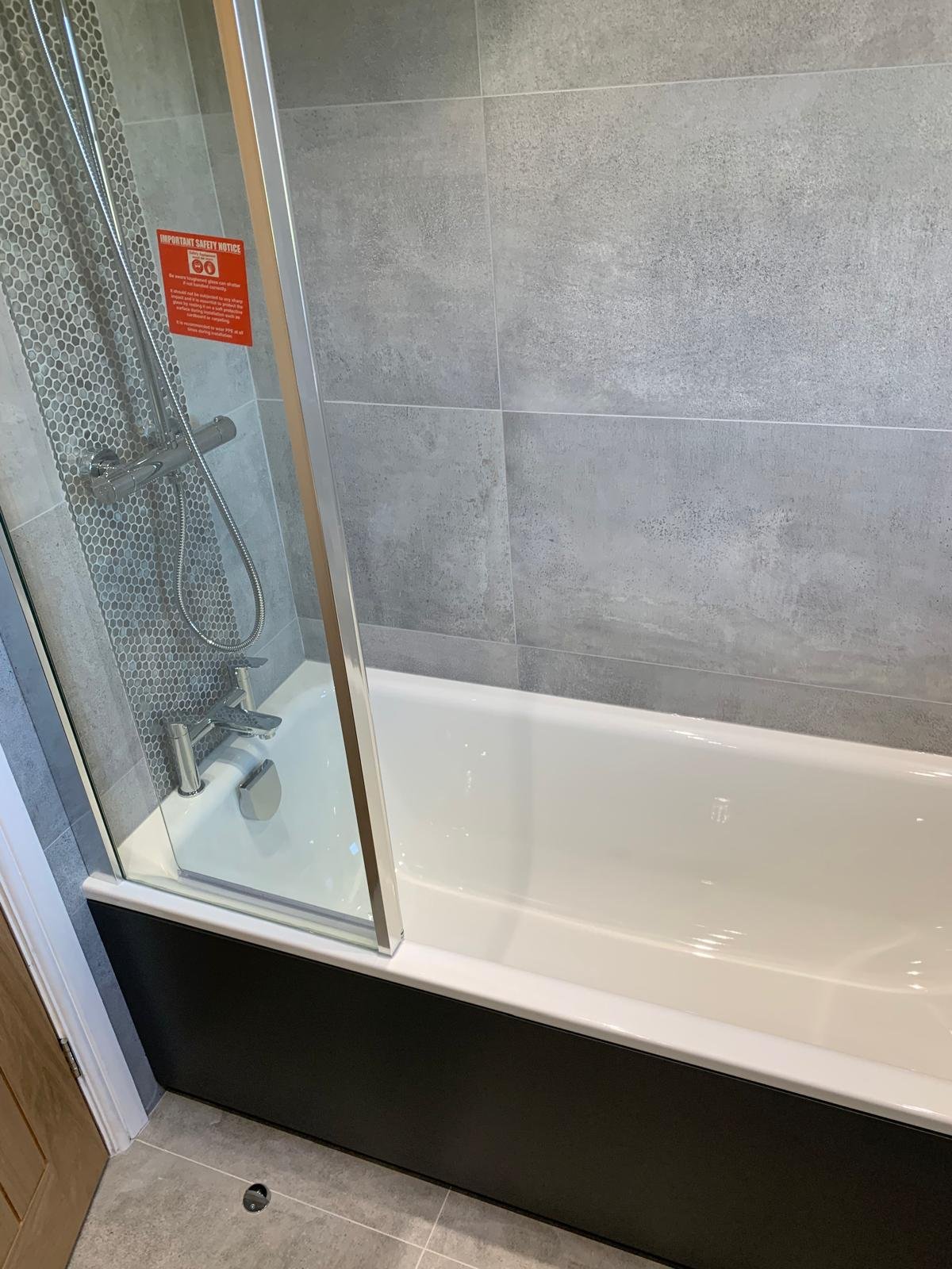 Shower over bath with a glass screen and mosaic tiled recess