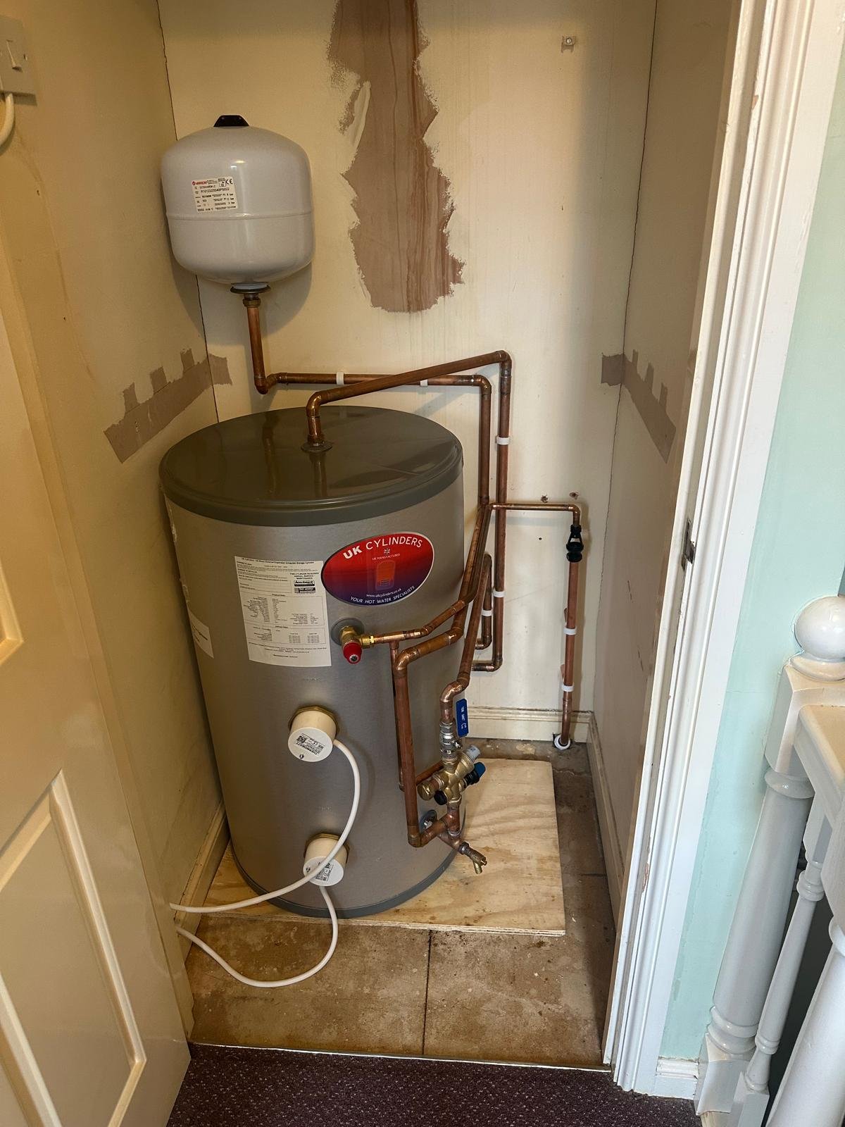 Unvented hot water cylinder and expansion vessel installed in an upstairs cupboard