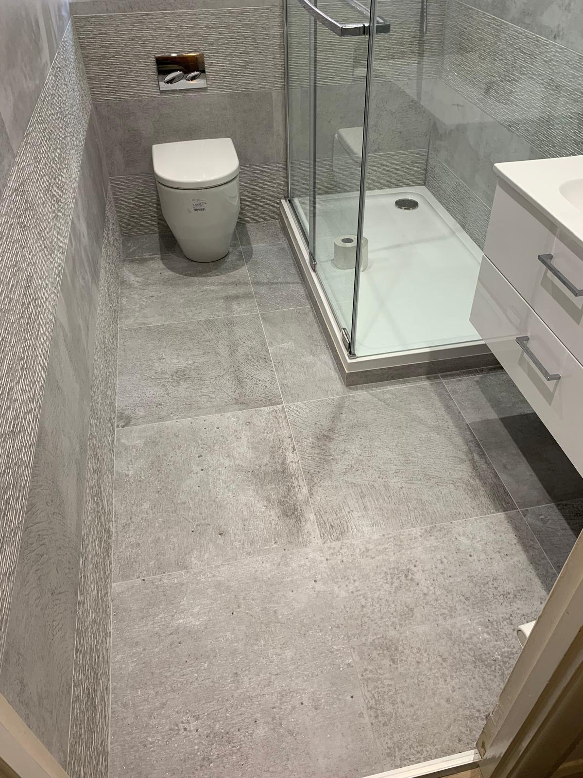 Shower room with a walk in enclosure, wall hung toilet and grey tiled floor