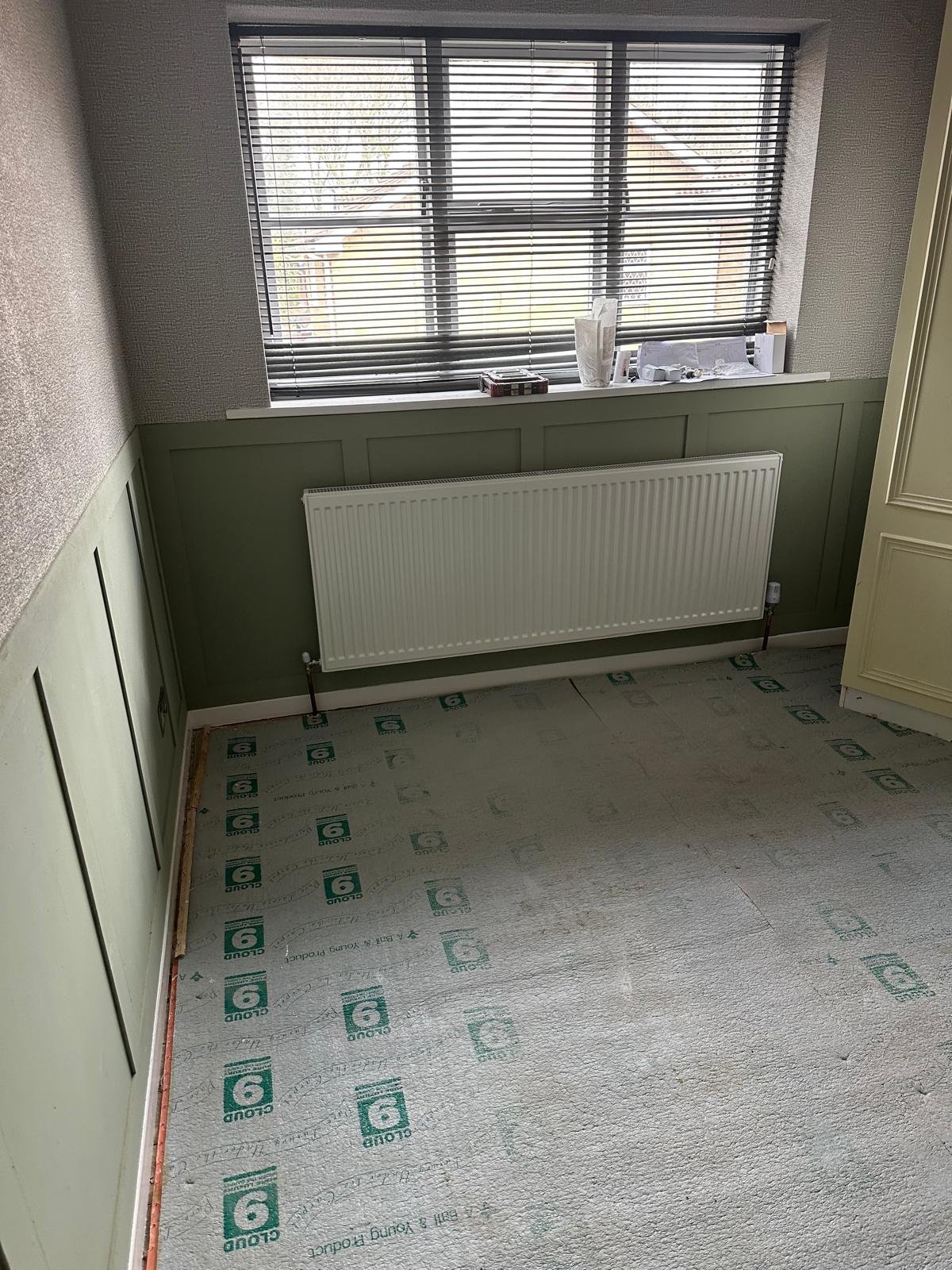 New double panel radiator fitted on a panelled wall with floor protection down