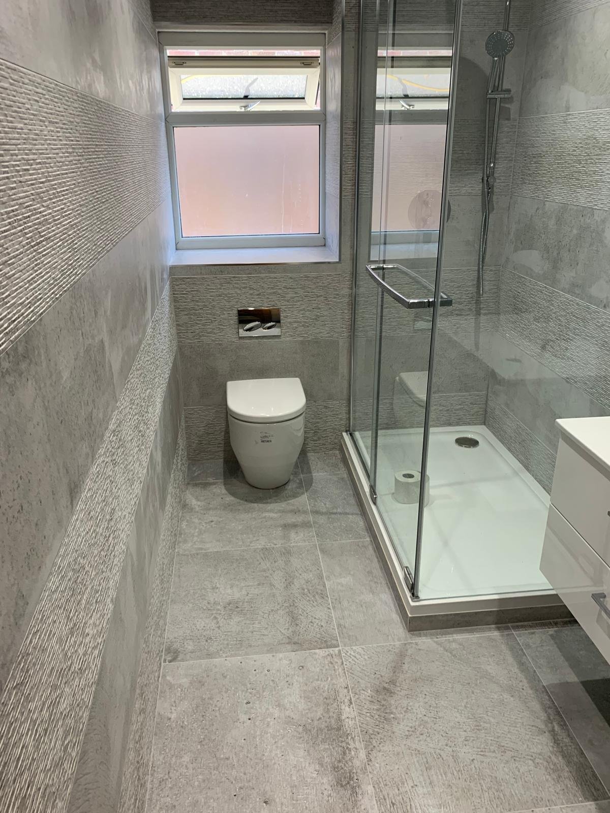 Completed shower room with a wall hung toilet and tiled walls