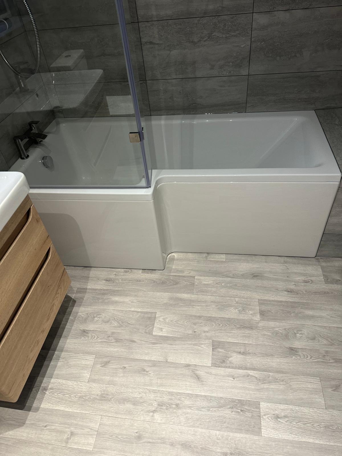 L shaped shower bath with an oak vanity unit and wood effect flooring